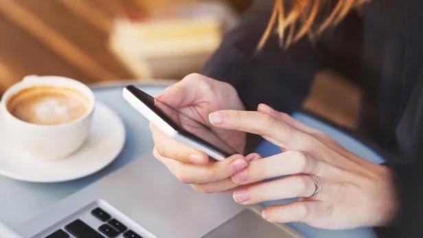 Girl sitting in a cafe and holding a smartphone, close-up